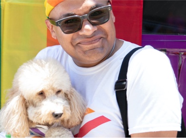 Man with dog in front of rainbow flag