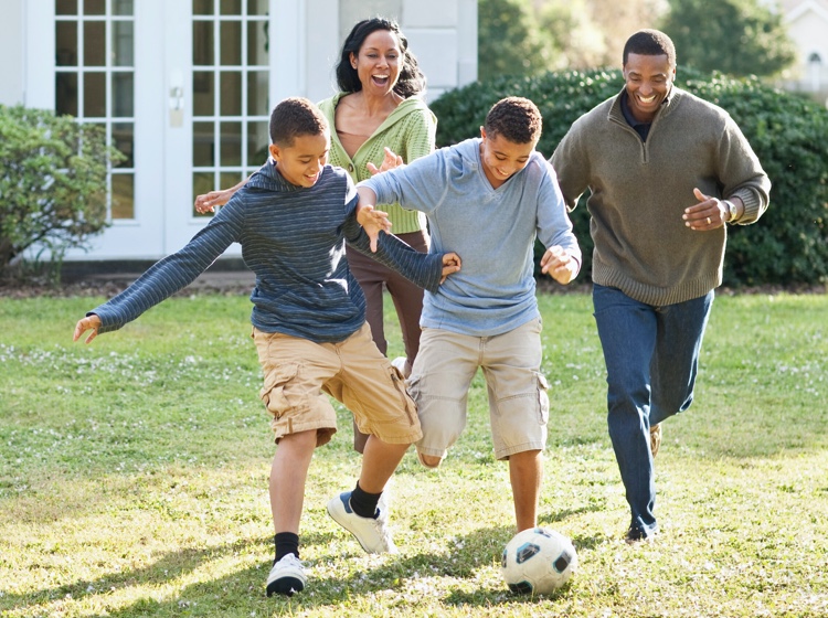 Family playing soccer in yard