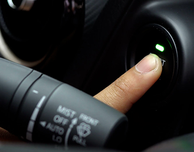 A finger pushing a car start button