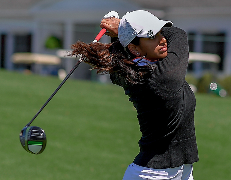 Female golfer swings golf club