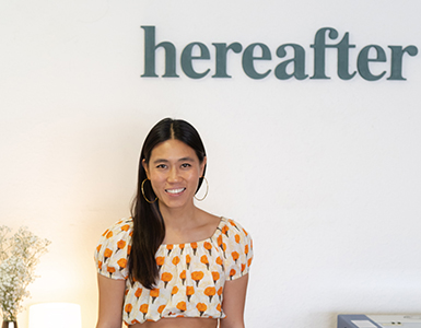 Entrepreneur Yvonne Leung standing under a sign with the name of her company, Hereafter.