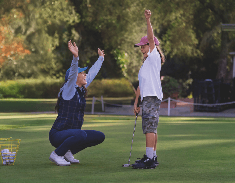A child and an adult celebrating a golf putt 