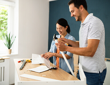 Two people assembling a wooden project at a workbench.