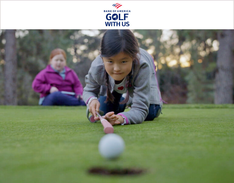Young girl focusing on hitting a golf ball