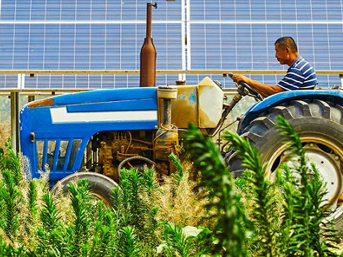 Man driving a tractor next to solar panels