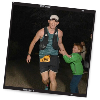 A Polaroid of Martin high-fiving a young boy while running a race