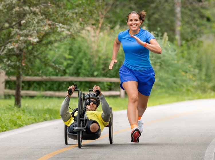 Tesa running alongside Zach while he handcycles