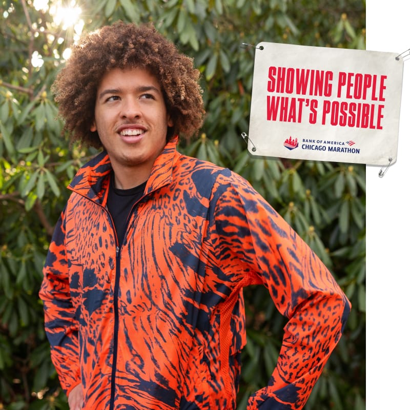 Conrad standing outdoors with an image of a bib that reads “SHOWING PEOPLE WHAT’S POSSIBLE”