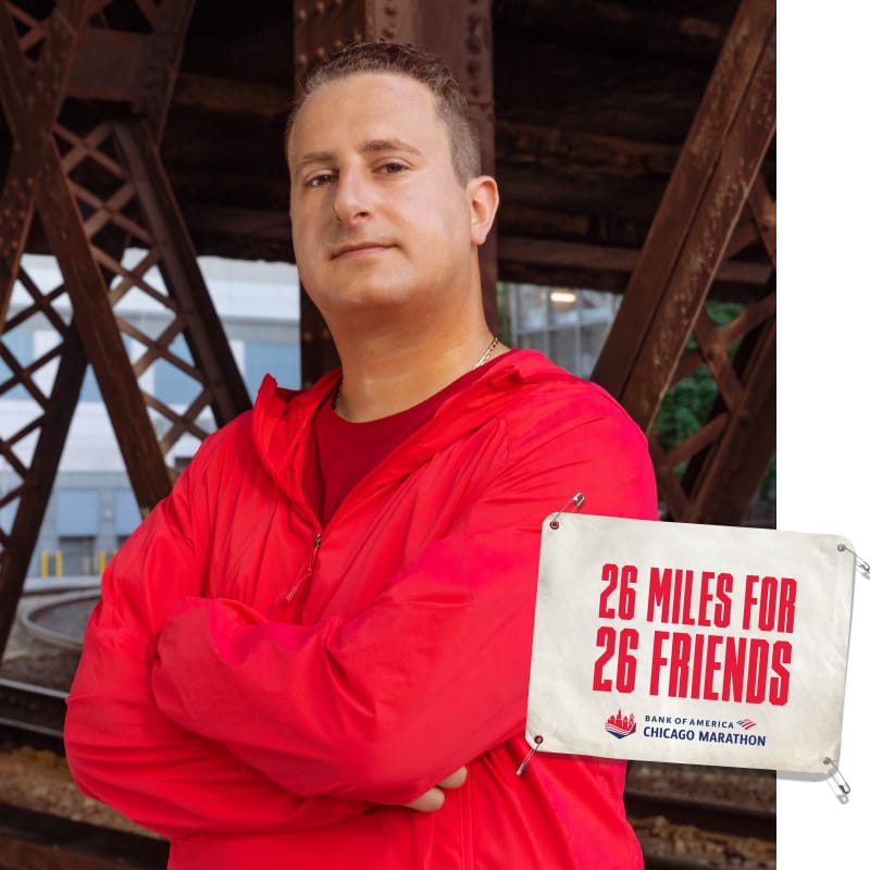 Joseph standing facing camera with an image of a bib that reads “26 MILES FOR 26 FRIENDS”