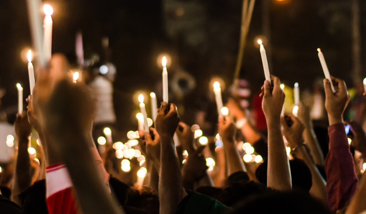Crowd of people holding candles in the air