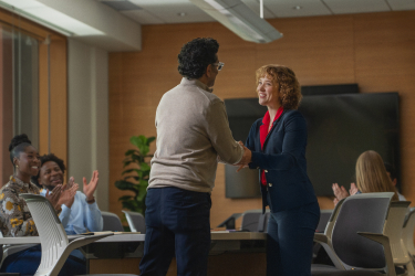 A support group leader cheerfully shaking hands with a participant
