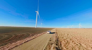 A windmill and car driving on road