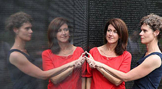 Two women touching memorial wall