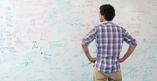 Man looking at whiteboard full of formulas