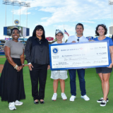 Five people holding a large check at Dodger Stadium in Los Angeles