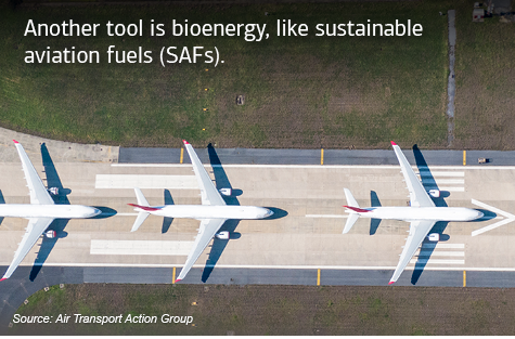 Three planes lined up on the runway. Text reads, “Another tool is bioenergy, like sustainable aviation fuels (SAFs).” With “Source: Air Transport Action Group,” at the bottom.