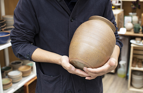 Person holding large pottery vase