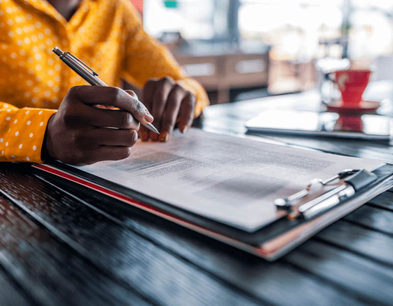 Closeup of person filling out paperwork on a clipboard