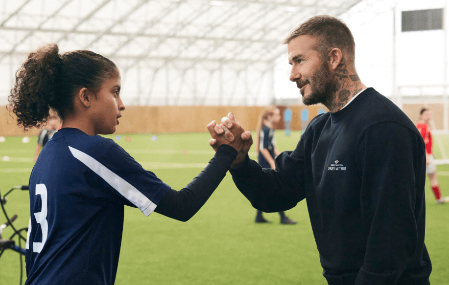 Sir David Bekham shaking hands with a young soccer player
