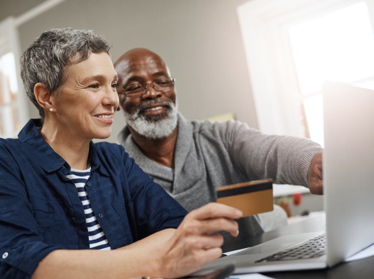 Man and woman holding credit card and looking at computer