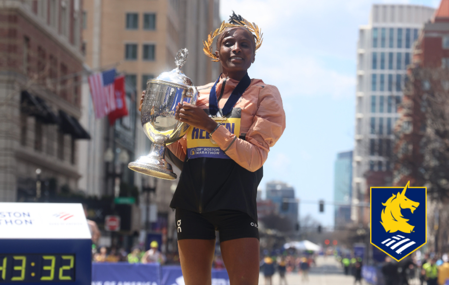 Boston Marathon winner lifting her cup trophy and logo for Boston Marathon