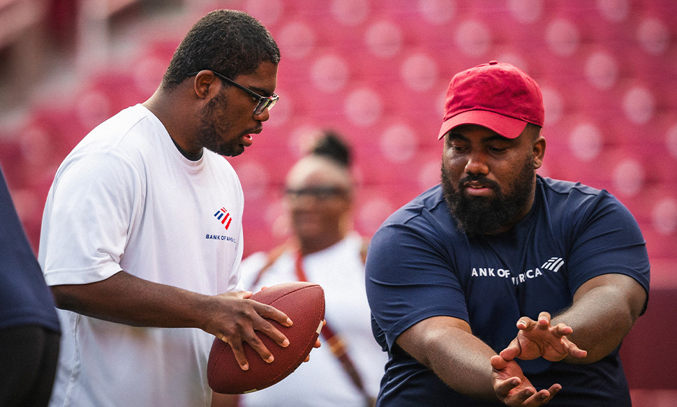 A young man showing another young man how to play football