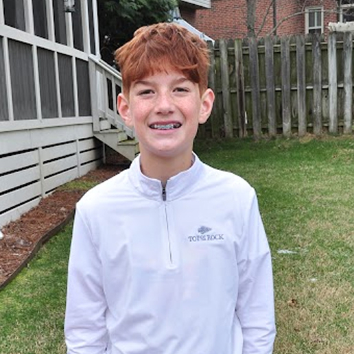 Youth golfer, Daniel B, smiles at the camera while on the green