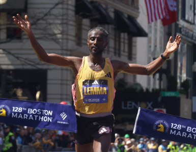 A Boston Marathon runner raising his arms as reaches the finish line