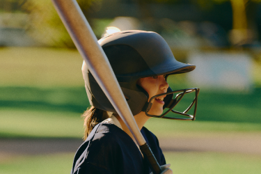 A young girl playing baseball, wearing a helmet and gripping a bat