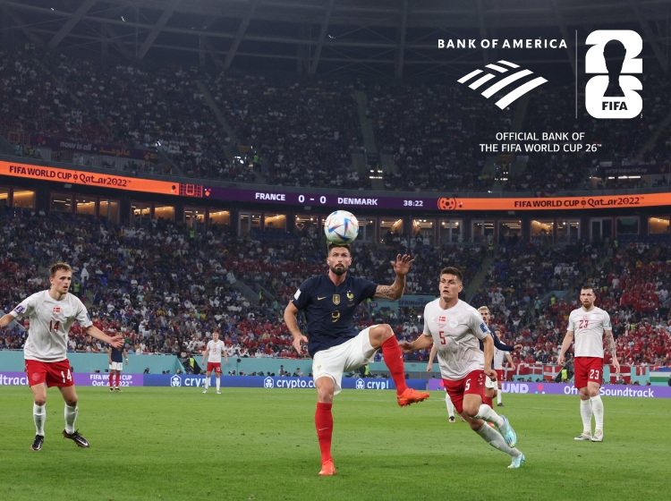 Photograph of a soccer match between two teams, showing players actively contesting the ball in a crowded stadium.