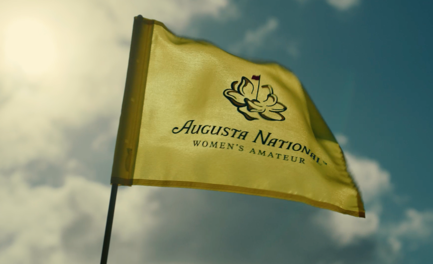 The Augusta National Women’s Amateur flag waving in the wind with a clear blue sky in the background