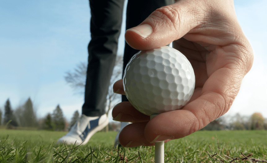 A hand placing a golf ball on a tee