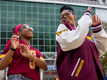 Two female Commanders fans celebrating outside of stadium