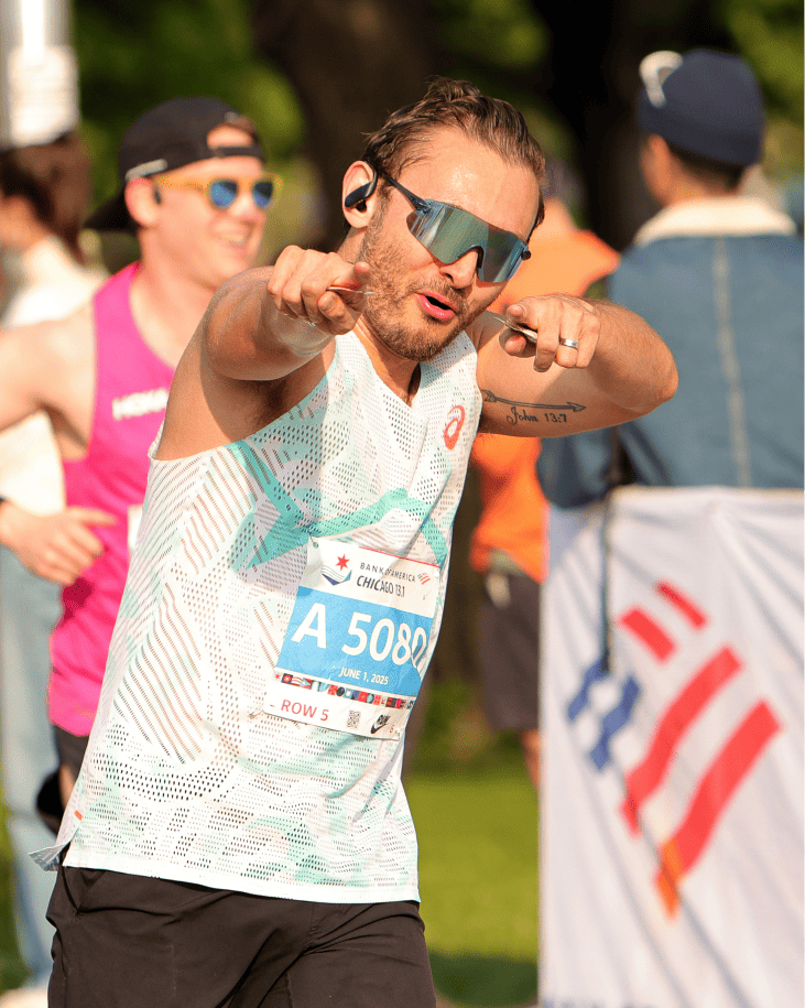 An athlete in a white tank top pointing at the camera