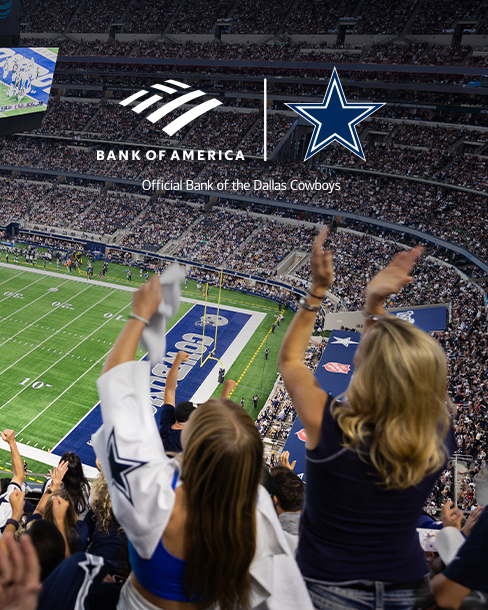 Two female Cowboys fans cheering with arms up facing the field