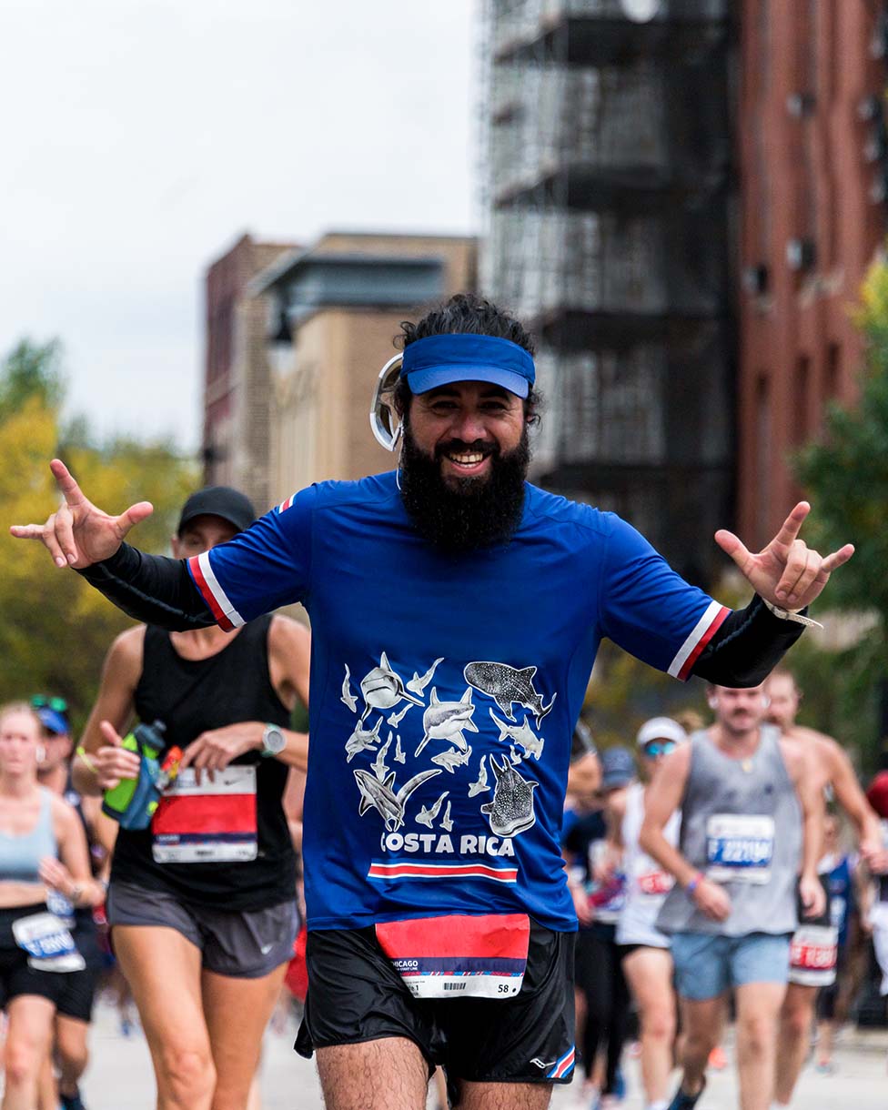 A runner is smiling as he runs through crowd