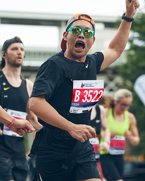 A runner is yells triumphantly as he runs through ​ crowd​
