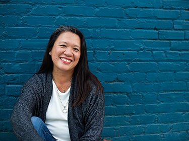 A person smiling in front of a blue wall