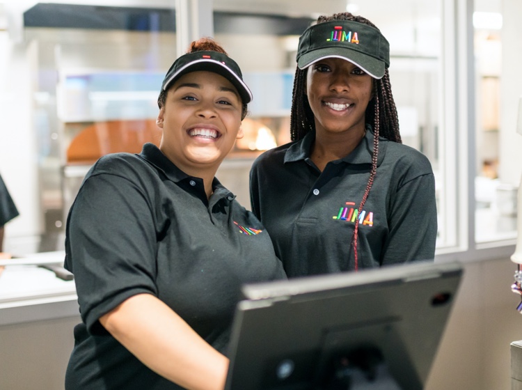 Two workers behind the counter, smiling.