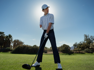 A 14-year-old golfer with one arm, Tommy Morrissey, tees off on a golf course.