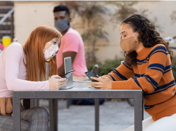two students wearing masks and talking together