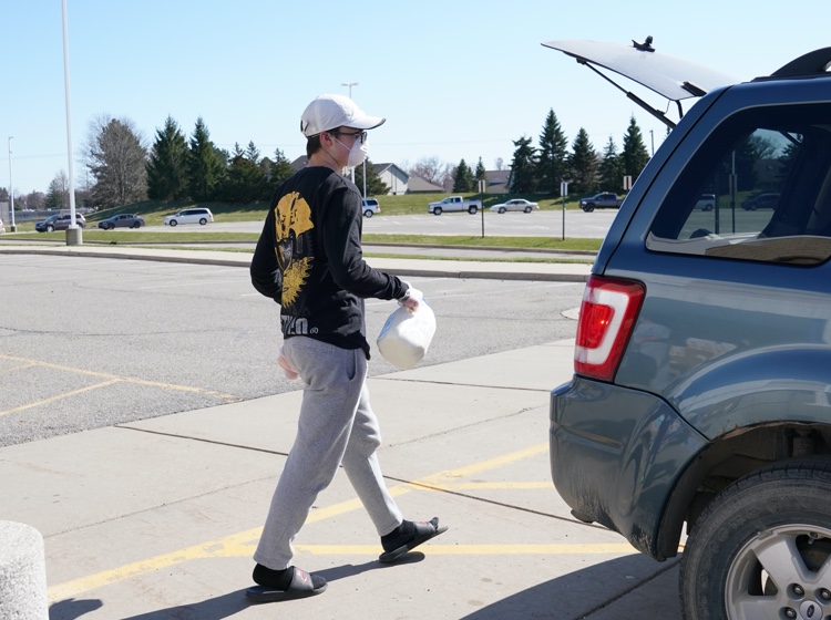 Volunteers loading groceries into car trunk