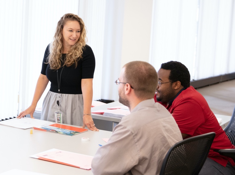 Woman speaking to two men in meeting