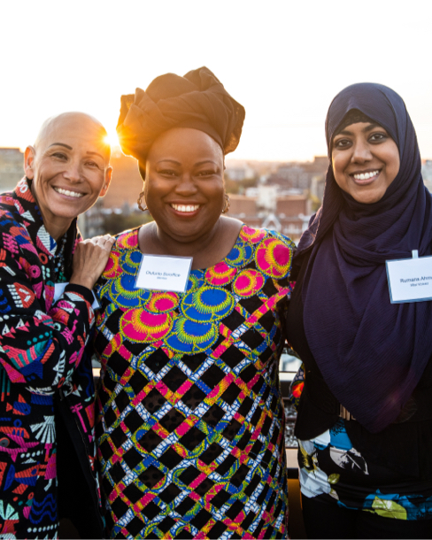 3 women smiling in front of a sunset