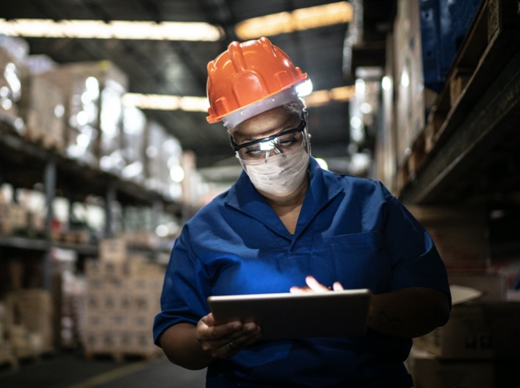 Worker in hard hat using a tablet in a warehouse