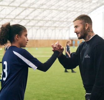 Sir David Bekham shaking hands with a young soccer player