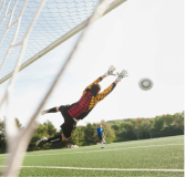 Soccer goalkeeper blocking a shot with outstretched arms