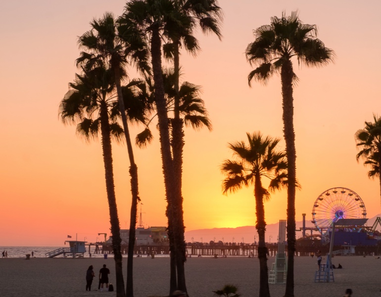 Beach with people and Ferris wheel at sunset