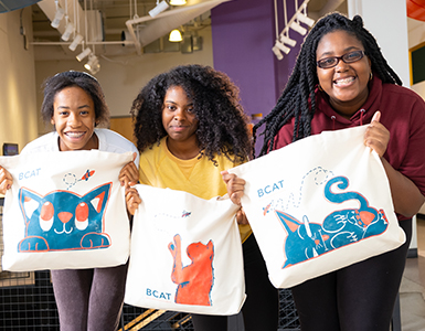 3 women smiling and holding BCAT bags