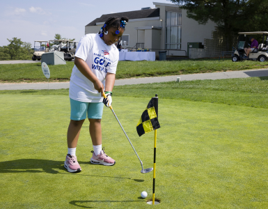 A young golfer putting a golf ball